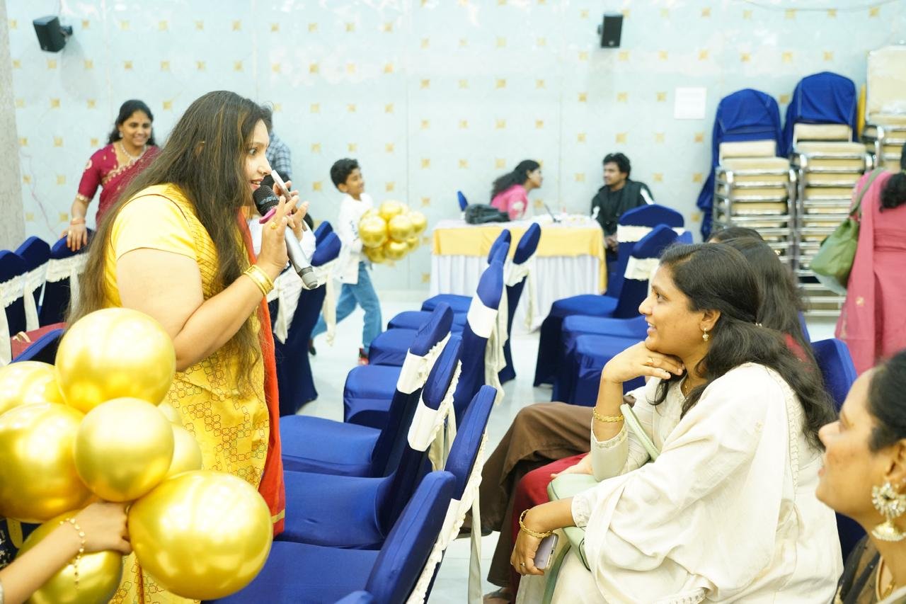 Pooja Aravalapalli moving through the audience with a microphone as a guest smiles up at her