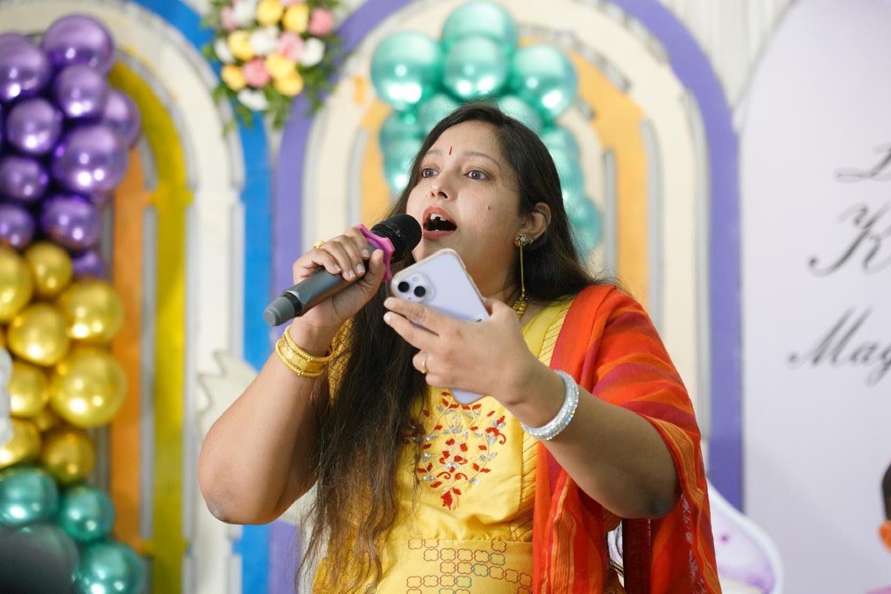 Pooja Aravalapalli anchoring with high energy in front of a balloon arch